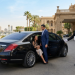 سائق يفتح باب سيارة مرسيدس فاخرة لعميلين أمام فندق فخم في القاهرة - خدمة إيجار مرسيدس بالسائق.